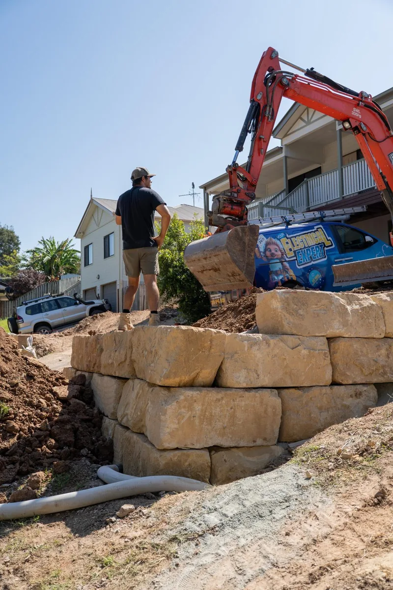 Sandstone retaining wall build in progress on a sloping block