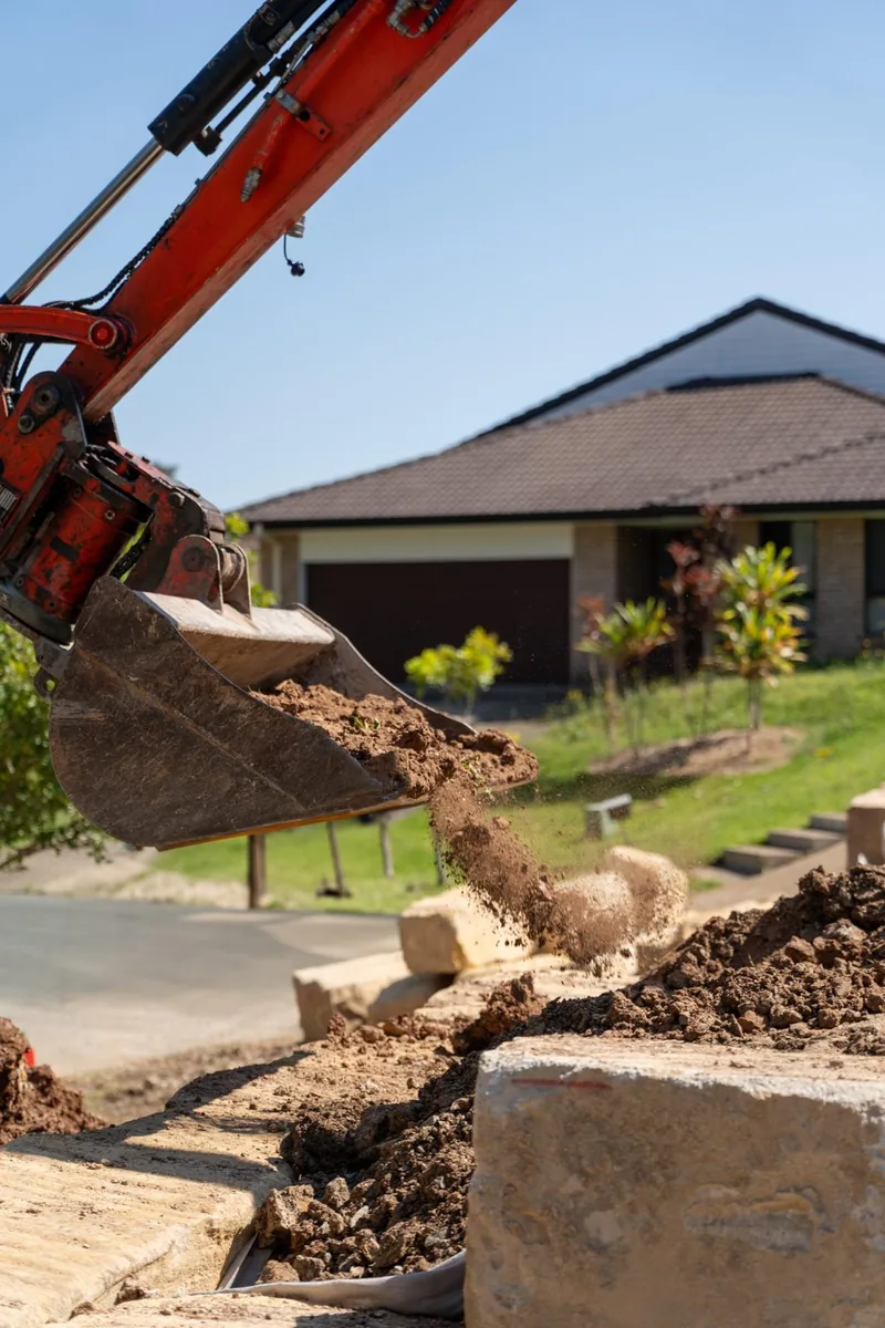 Excavator working alongside a driveway during residential earthworks