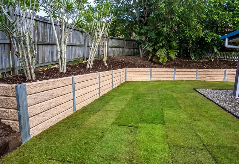 Completed sandstone block retaining wall with new turf laid in a Gold Coast backyard