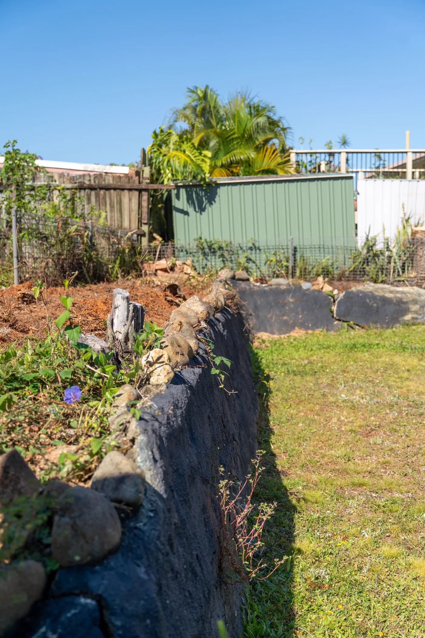 Steep unretained slope beside a Gold Coast home before retaining wall works
