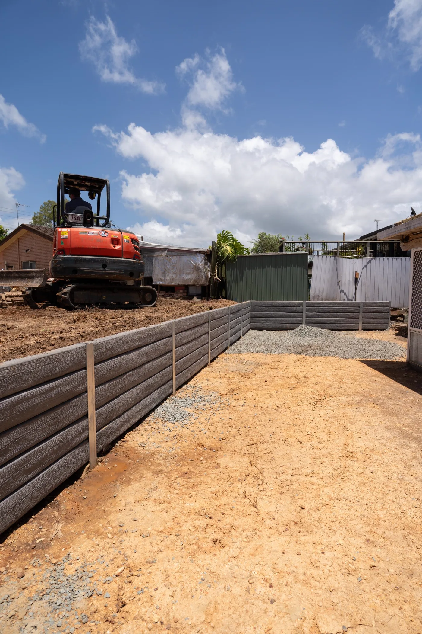 Retaining wall being built in stages with drainage aggregate behind the sleepers